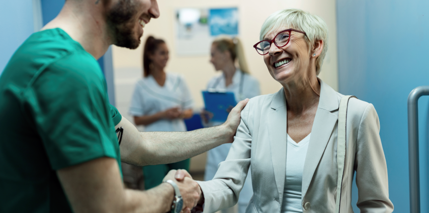 A Doctor In Apron Shaking Hand With An Cheerful Old Lady